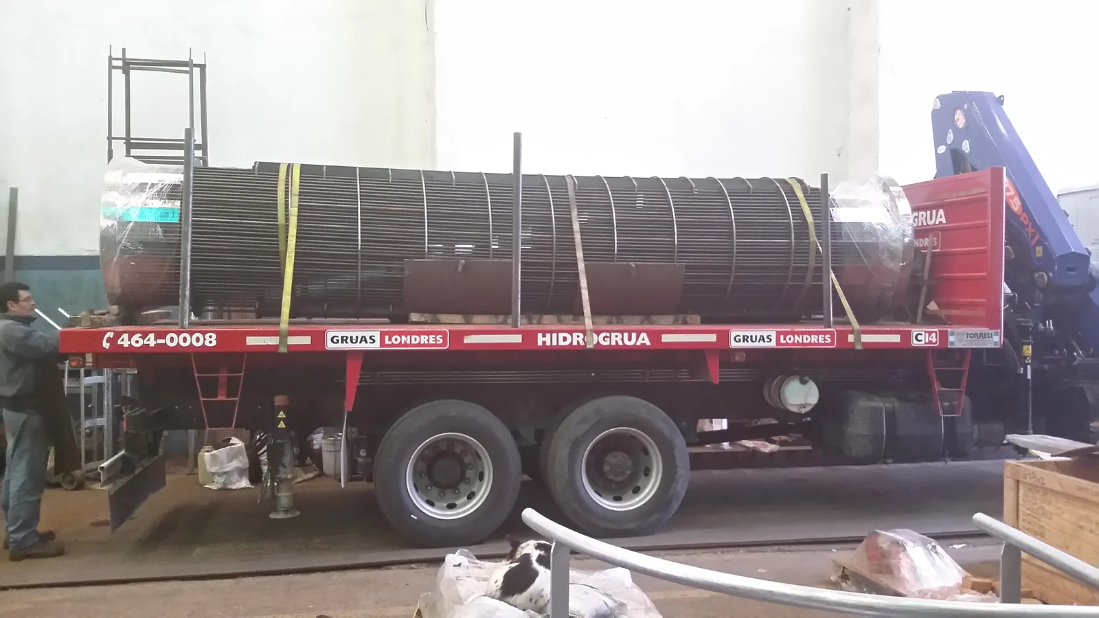 Haz tubular de gran longitud cargado sobre camión con hidrogrúa, trincado para el traslado