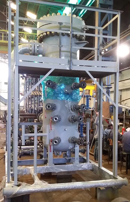 Recipiente vertical con múltiples conexiones bridadas sobre estructura con plataforma