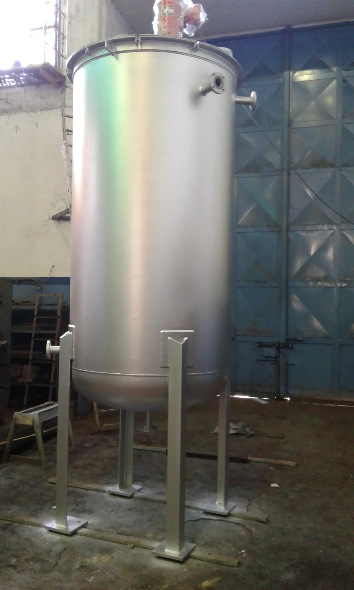 Tanque vertical esbelto sobre patas con tapa superior y conexiones bridadas