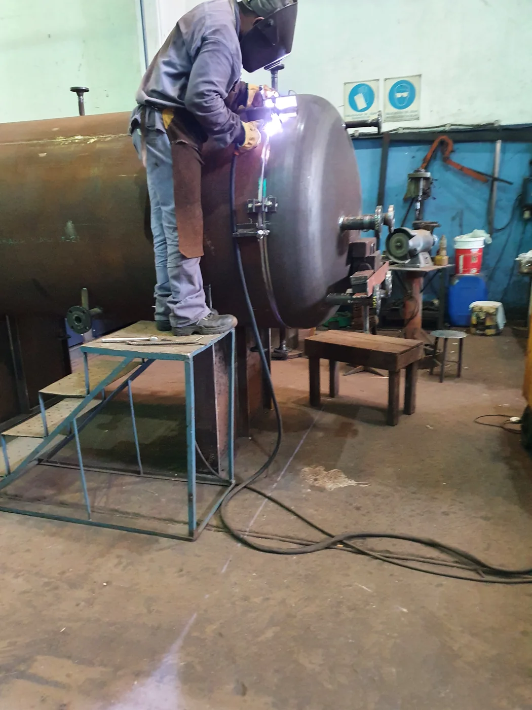 Soldador sobre plataforma soldando el casquete al cuerpo del recipiente