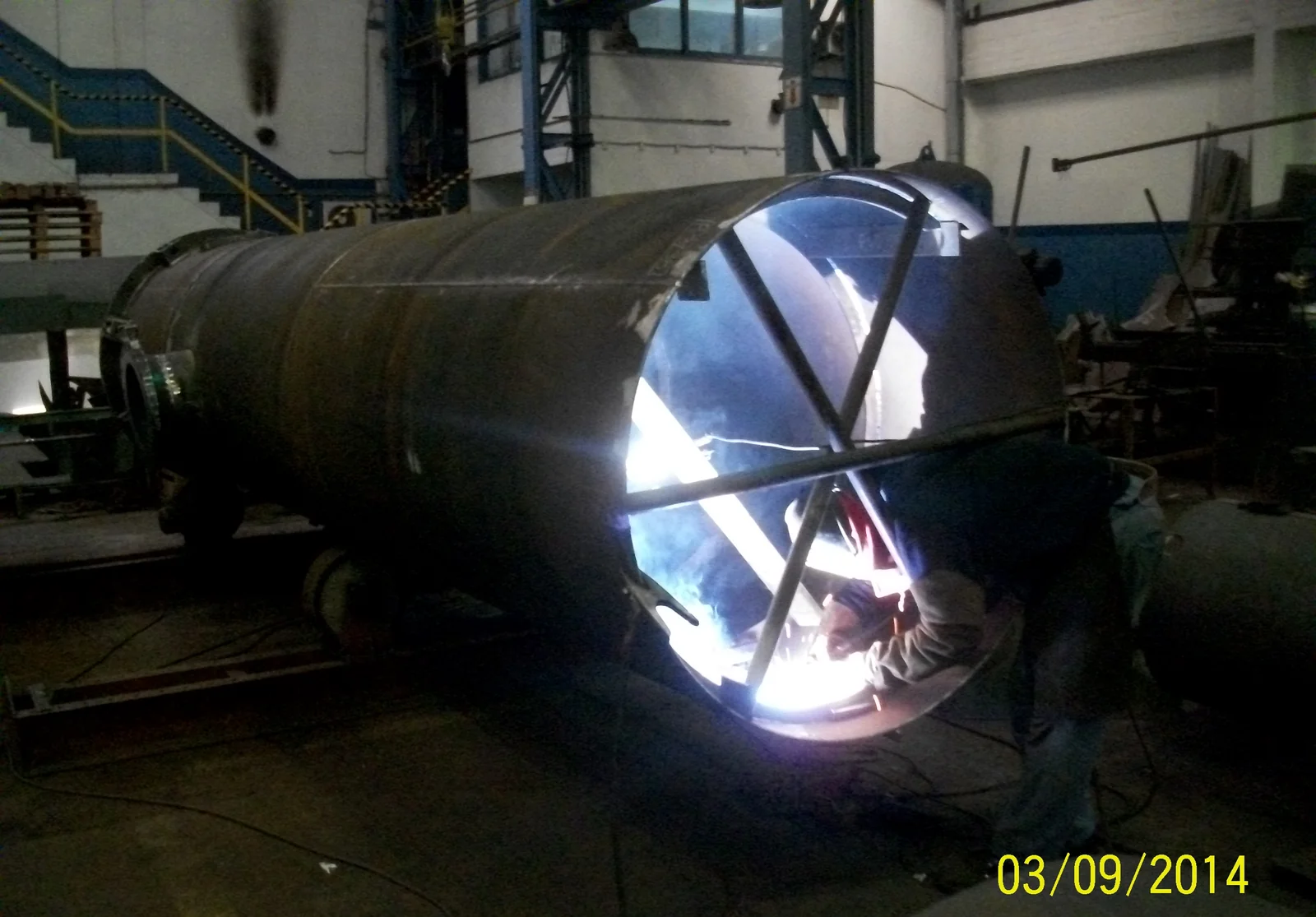 Soldador trabajando dentro del cuerpo de un recipiente